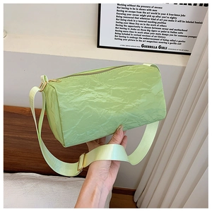 Minimalist light green cylinder crossbody bag with textured fabric and wide shoulder strap