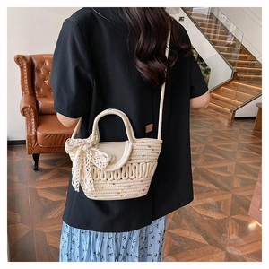 Detailed shot of beige woven bucket bag with colorful embroidery and lace bow accent