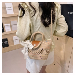 Detail of woven straw bag with leather flap, pearl button and white lace bow accessory