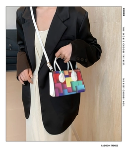 Detail of colorful geometric print handbag with white straps and gold metal hardware
