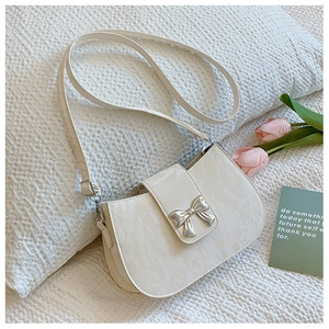 Dettaglio della borsa bianco crema con chiusura a fiocco in metallo e trama elegante
