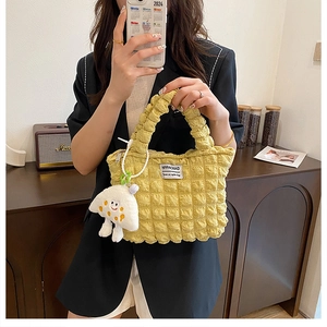 Close-up of yellow bubble textured handbag with a cute mushroom plush pendant detail