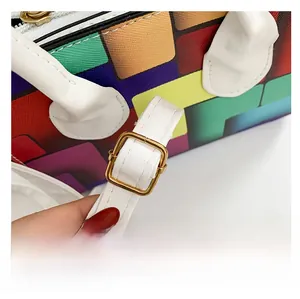 Detail of adjustable white leather strap with gold buckle on colorful geometric handbag