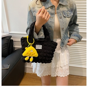 Detail of black puff bubble texture handbag with a cute yellow mushroom plush charm