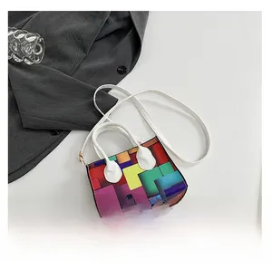 Detailed view of colorful geometric block pattern mini bag with white top handles and strap