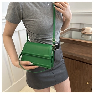 Detail of green leather flap crossbody bag with adjustable strap and gold hardware