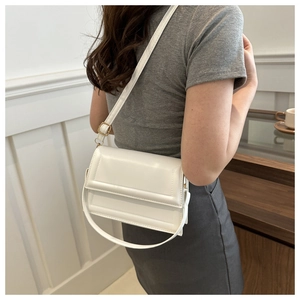 Minimalist white PU leather crossbody bag shown on model with adjustable strap and gold buckle