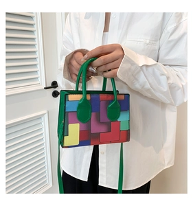 Detail of colorful geometric pattern and green leather handles on a stylish handbag