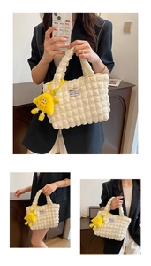 Detalle de la textura plisada blanca y el colgante de peluche amarillo en el bolso