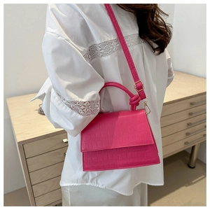 Close-up of fuchsia crocodile pattern crossbody bag with knot handle and gold buckle