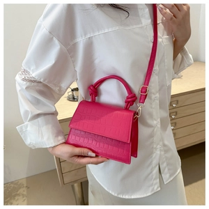 Detail of fuchsia mini square bag with crocodile pattern and stylish knot handle