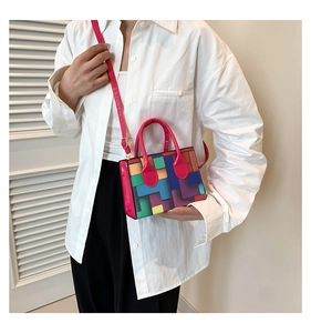 Detail of colorful geometric pattern handbag with pink strap worn across the body