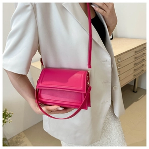 Close-up of bright pink leather crossbody bag paired with a white blazer for elegant style