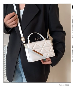 White quilted square bag with gold hardware and creative clip charm on casual model