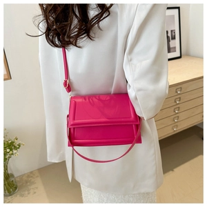 Detail of fuchsia leather crossbody bag featuring adjustable straps and polished finish