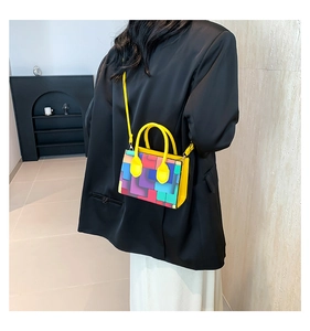 Detail of colorful geometric block pattern and yellow handle on a stylish crossbody bag