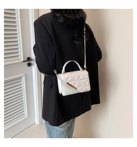 Detail showing white quilted leather texture and elegant gold metal trim on the handbag