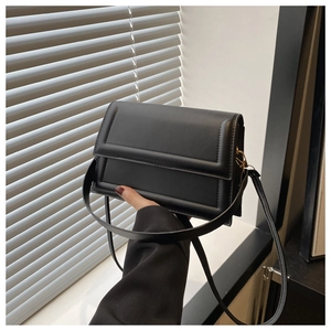 Dettaglio di una borsa a tracolla nera minimalista con patta a rilievo rettangolare