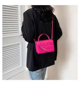 Magenta quilted crossbody bag with gold metal trim shown on model in black blazer