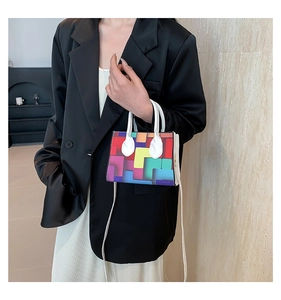 Detail of colorful geometric block pattern handbag with white strap on black blazer