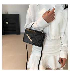 Detail of black quilted shoulder bag featuring elegant gold metal trim and leather texture