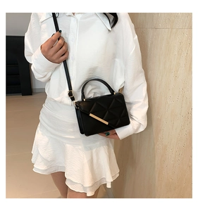 Close-up of a black quilted crossbody bag with gold hardware and fine stitching detail