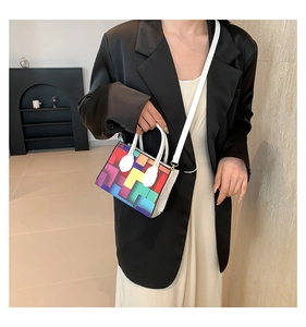 Detail of colorful geometric block pattern on a white mini handbag worn with a blazer
