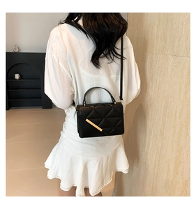 Classic black quilted leather crossbody bag with gold metal trim worn by model