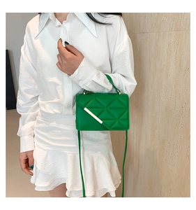 Detailed close-up of vibrant green quilted PU leather handbag with gold metal bar accent