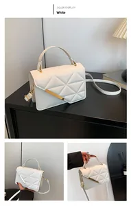 Detailed view of white quilted crossbody bag with gold metal trim and chic top handle