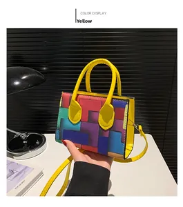 Detail of colorful geometric block pattern handbag with yellow cylindrical handle