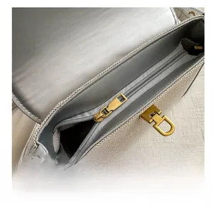Detail showing smooth gold metal zipper and twist lock on woven grey crossbody bag