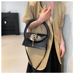 Modern black leather square bag with unique circular handle and gold metal detail