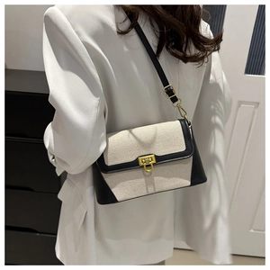 Detail of canvas shoulder bag with black leather trim and elegant gold metal lock