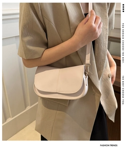 Dettaglio di una borsa a tracolla crema minimalista in pelle opaca con fibbia oro