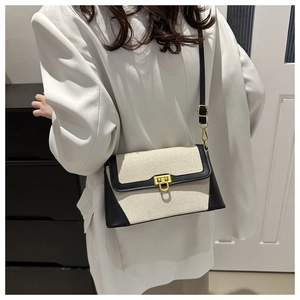 Detail of a contrast canvas square bag featuring a gold twist lock and black leather trim