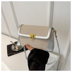 Detail of the chic contrast stitching lock crossbody bag with cream fabric and silver trim