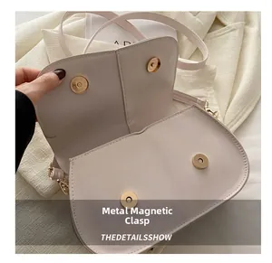 Dettaglio delle fibbie magnetiche dorate sulla borsa a mano in pelle color crema
