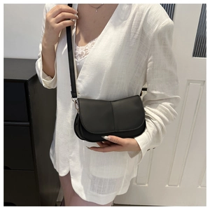 Borsa a tracolla minimalista in pelle opaca nera abbinata a un outfit con blazer bianco