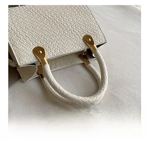Detail of woven texture on cream faux leather handbag with golden metal hardware