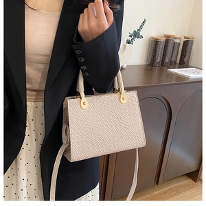 Elegant beige croc-embossed handbag styled with a suit for a professional business look