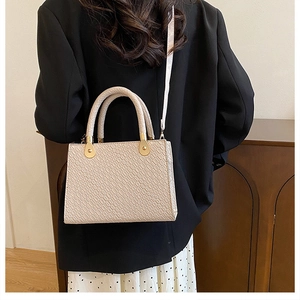 Close-up of beige crocodile embossed handbag with sleek gold hardware and crossbody strap