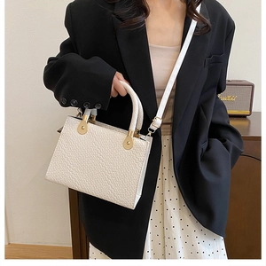 White woven leather handbag with gold hardware styled with a black blazer for a business look