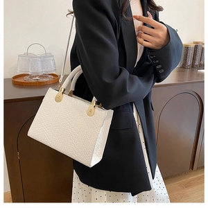 Elegant white woven leather handbag with gold hardware shown on a stylish model