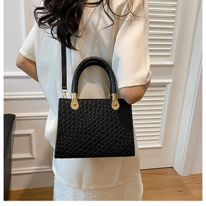 Detail of woven texture black patent leather handbag shown on model against white background