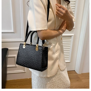 Close-up of elegant black crocodile texture leather handbag with gold metal hardware