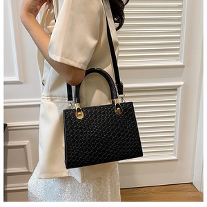 Detail of black faux leather handbag with woven texture and gold metal hardware