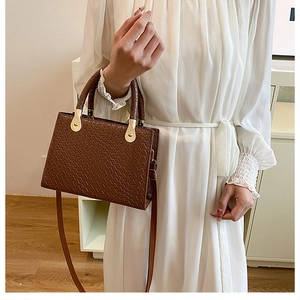 Detailed view of dark brown faux crocodile leather bag with gold hardware and top handle