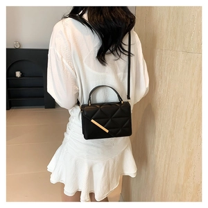 Chic black quilted crossbody bag with gold hardware and top handle shown on model