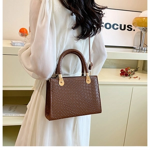 Detailed view of brown crocodile texture handbag with gold hardware and structured handle